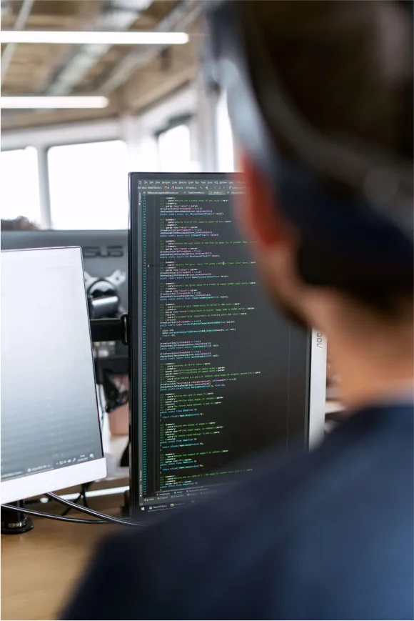 An image of a man overlooking some computer code written on a monitor